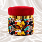 Single round ottoman stool with a red velvet seat, reflective gold band and multicoloured abstract upholstery on white satin fabric.