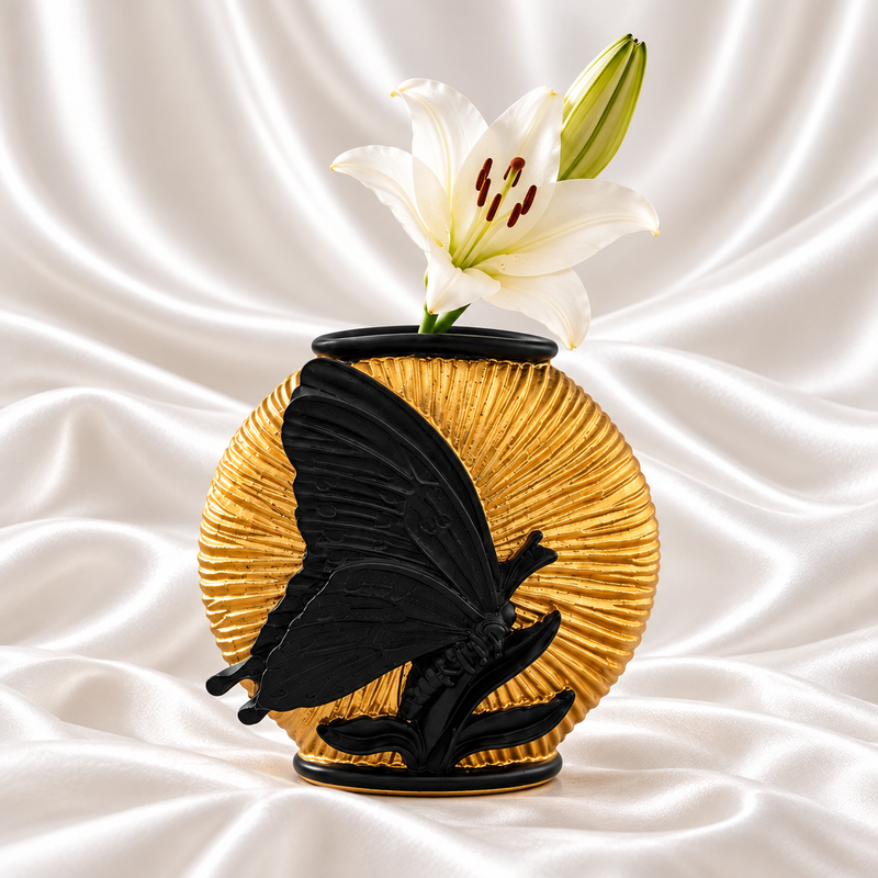 Gold ribbed vase with a raised black butterfly and white lily on a white satin background.
