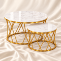 Luxury gold geometric nesting coffee tables set of 2 featuring round white marble-effect tops, elegant gold metal frames and an off-white satin fabric background – Decoreway.