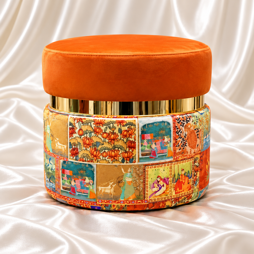 Single orange upholstered ottoman stool with a gold-tone band and colourful patchwork base on a white satin background.