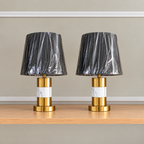 Pair of 28 inch luxury black and gold marble table lamps with black shades displayed on a white satin fabric background.
