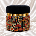 Single round black velvet ottoman stool with a gold-finish accent band and multicolour geometric printed base.