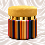 Luxury mustard velvet ottoman stool with gold accent band and multicolor striped round base on white satin background