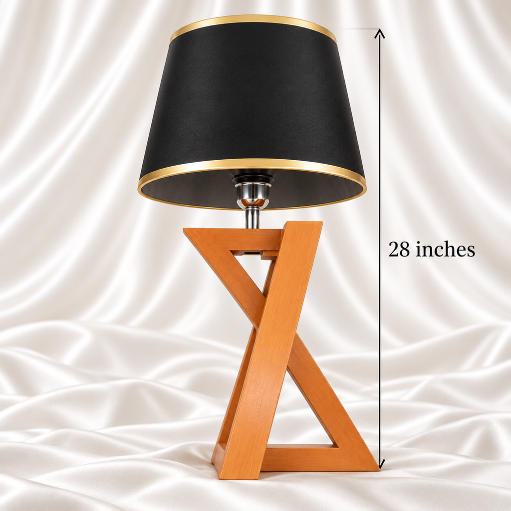 Single 28-inch table lamp with a black and gold-trimmed shade and wooden X-frame base on white satin fabric.