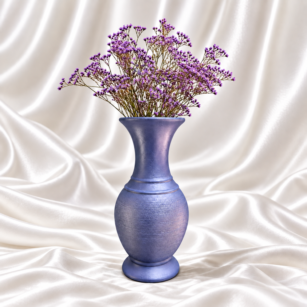 10-inch periwinkle blue decorative vase with a textured body and purple flowers on a white satin background.