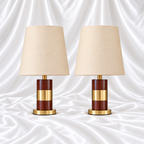 Pair of brown woodgrain-look table lamps with wide gold-tone centre bands, round gold bases and plain cream tapered shades on white satin fabric.