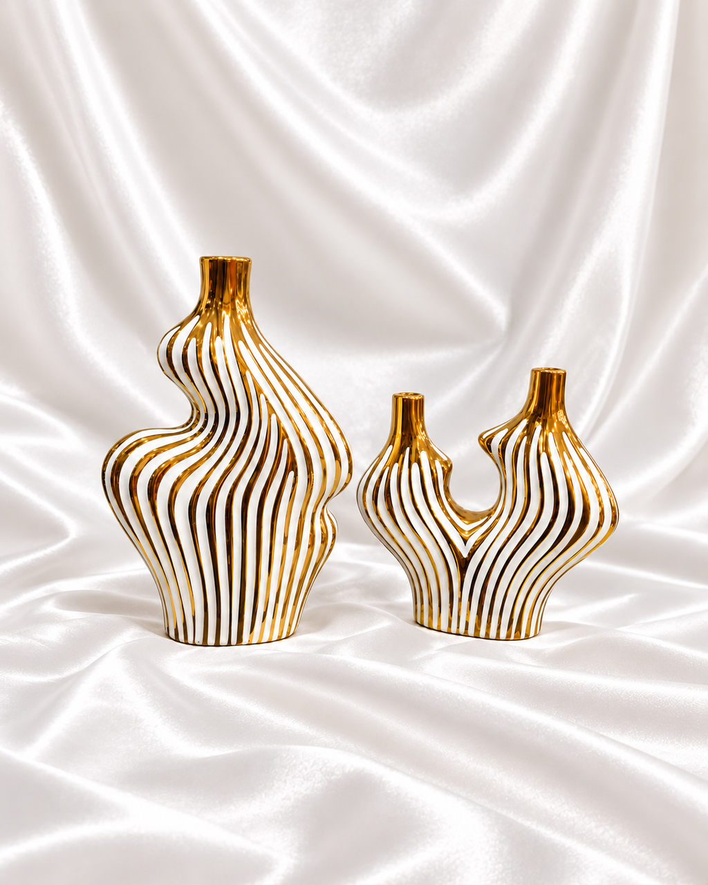 Set of two sculptural white vases with gold wave stripes displayed against a decorative shop background