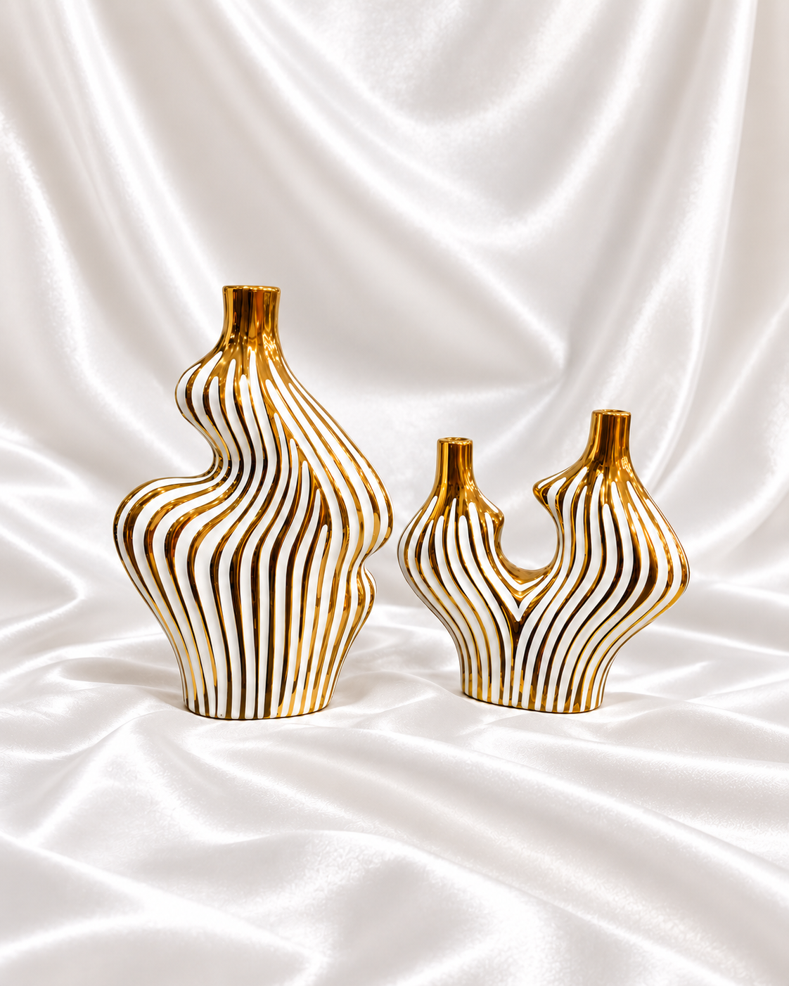 Set of two sculptural white vases with gold wave stripes displayed against a decorative shop background