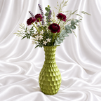 12-inch olive green resin decorative vase with a sculpted surface, styled with burgundy flowers and foliage on white satin fabric. Flowers not included.