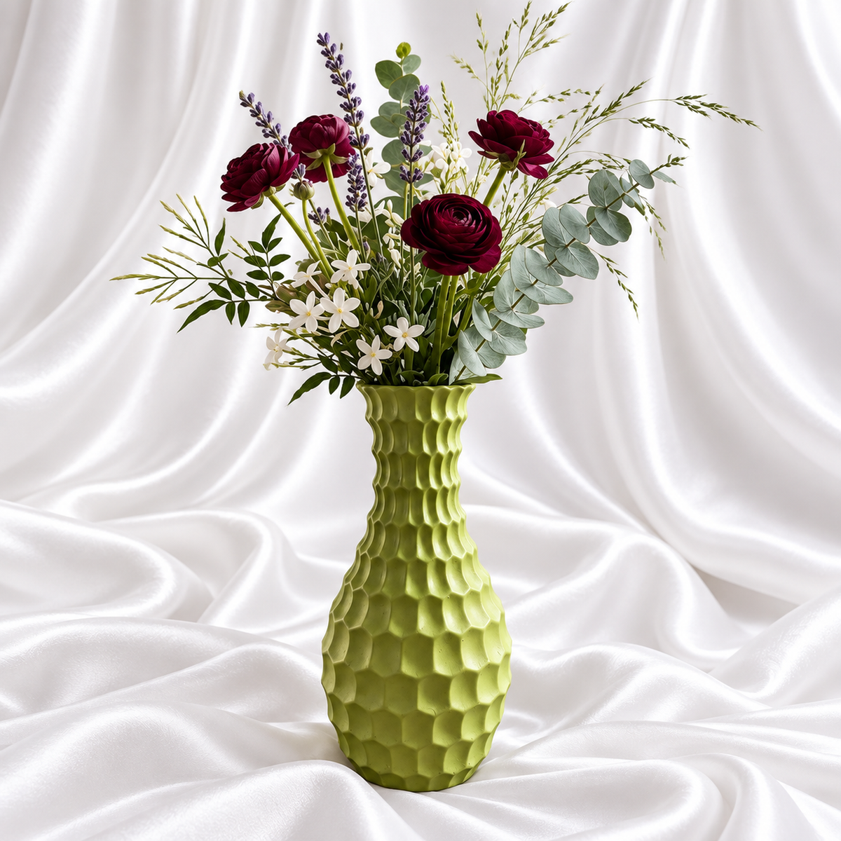 12-inch olive green resin decorative vase with a sculpted surface, styled with burgundy flowers and foliage on white satin fabric. Flowers not included.