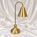 Luxury golden table lamp with elegant cone shade and curved stand on white satin background.