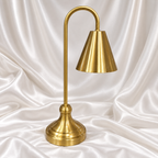 Luxury golden table lamp with elegant cone shade and curved stand on white satin background.