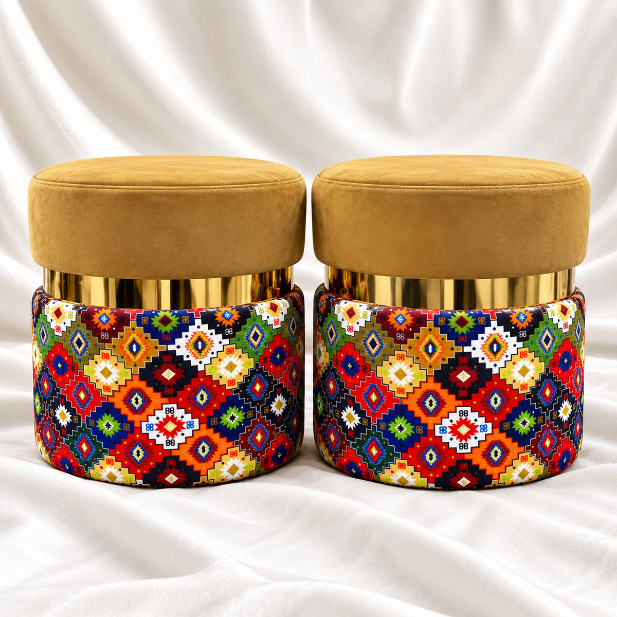 Set of 2 luxury mustard gold velvet ottoman stools with gold accents and colourful geometric fabric upholstery on white satin background.